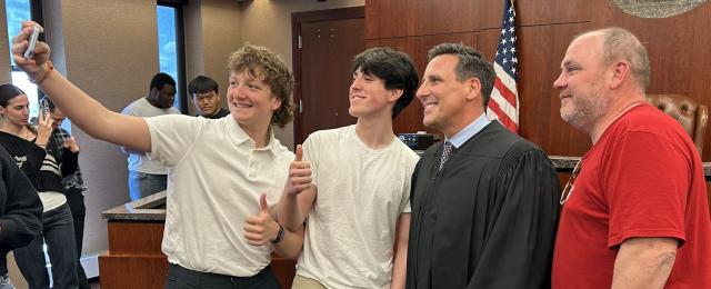Students and educators posing for selfies with a judge.